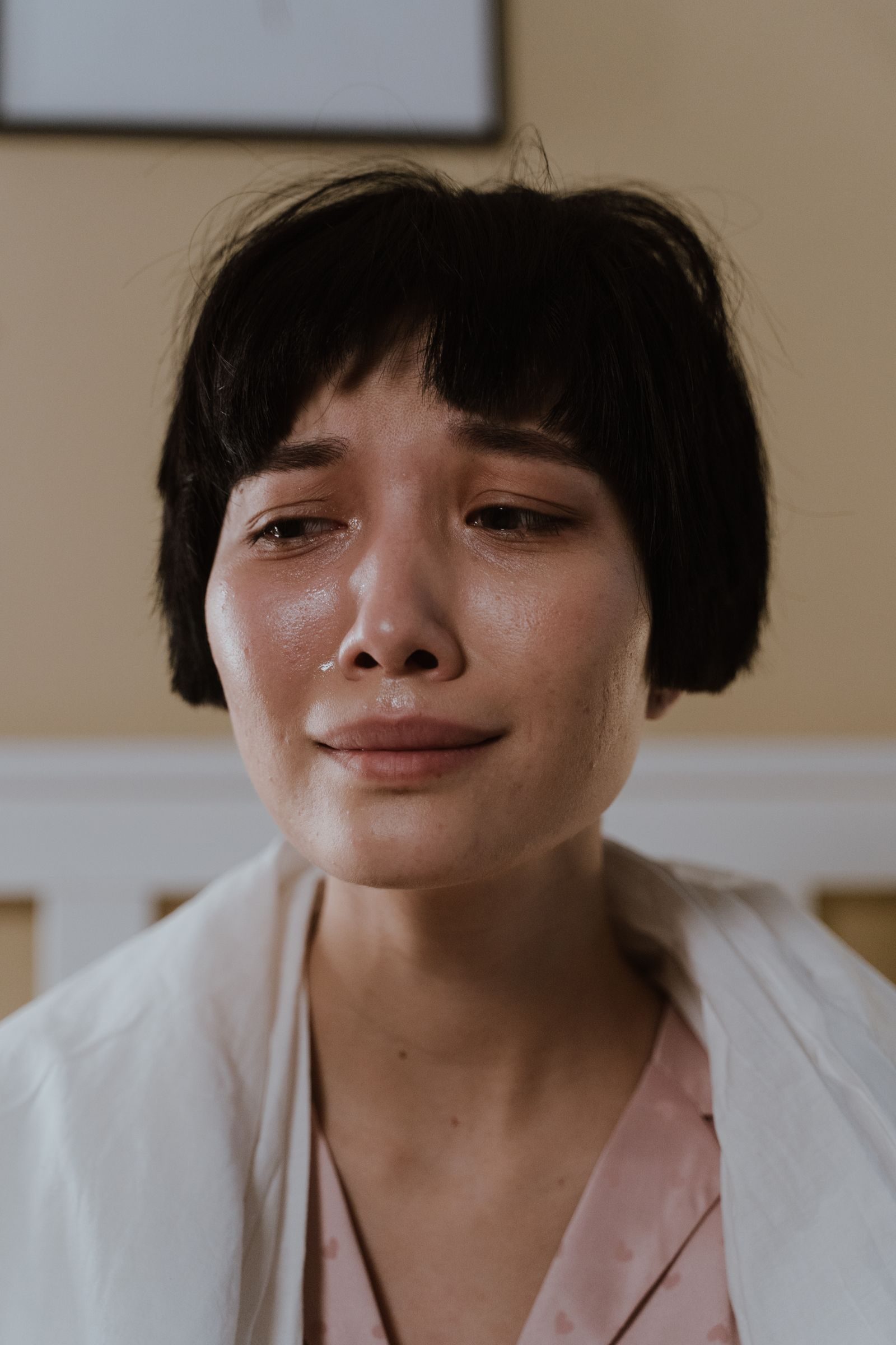 Close-up portrait of a crying woman indoors, showcasing emotions and vulnerability.