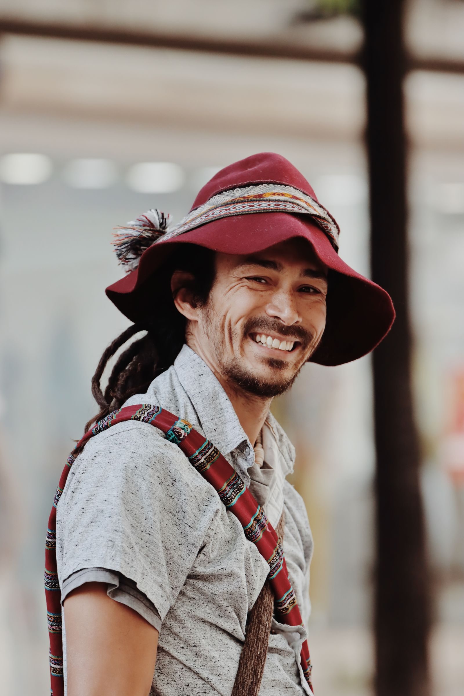 Portrait of a smiling man in a colorful hat, captured in Lisbon's lively streets.
