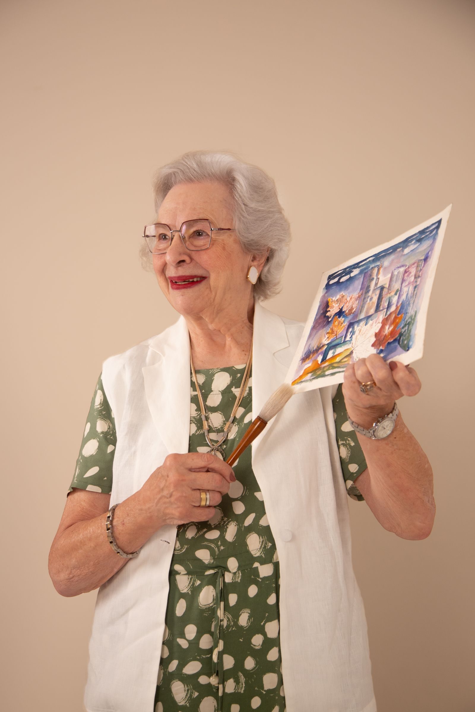 Happy senior woman proudly displays her watercolor art piece.