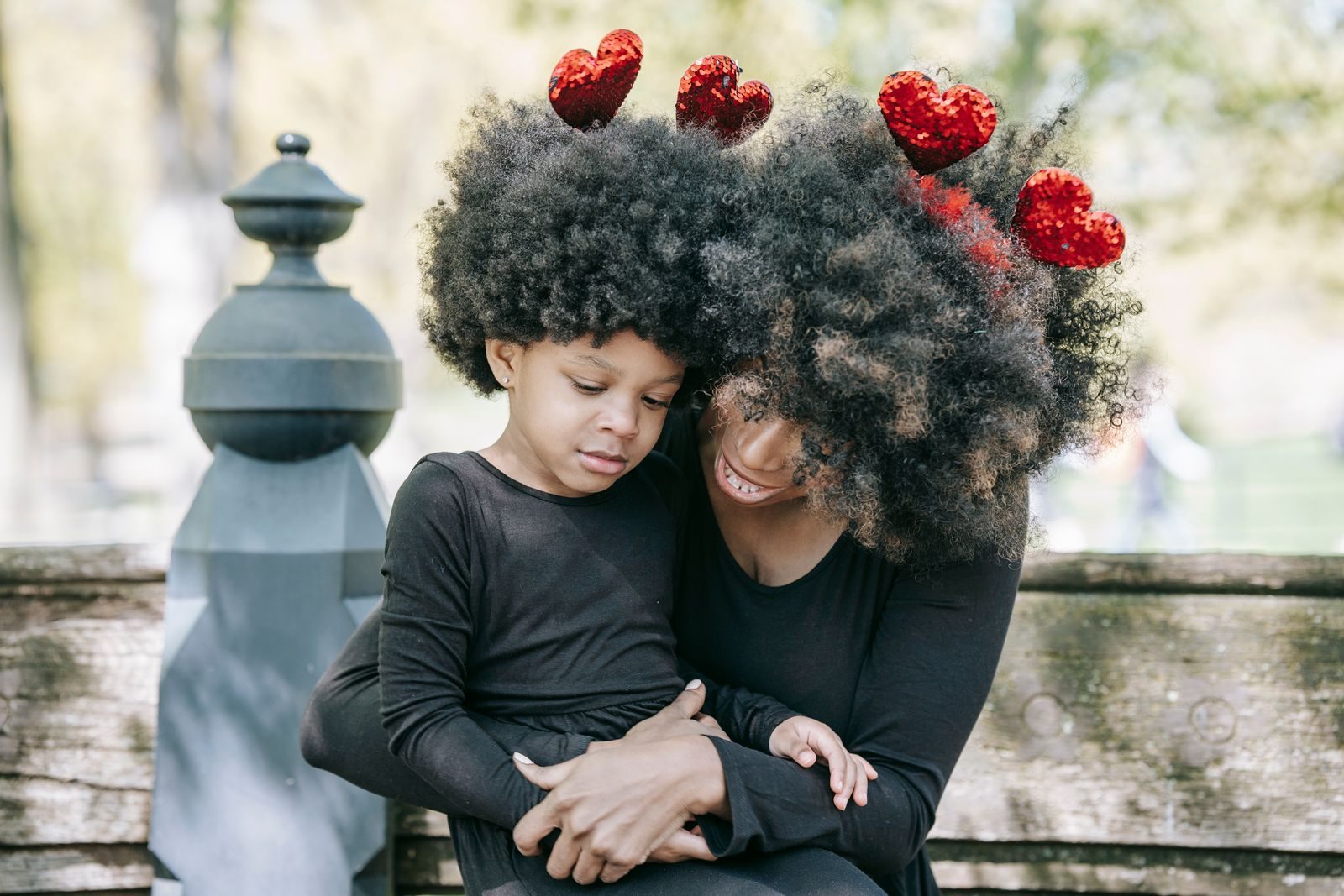 A mother and daughter with heart decorations share a loving embrace outdoors.