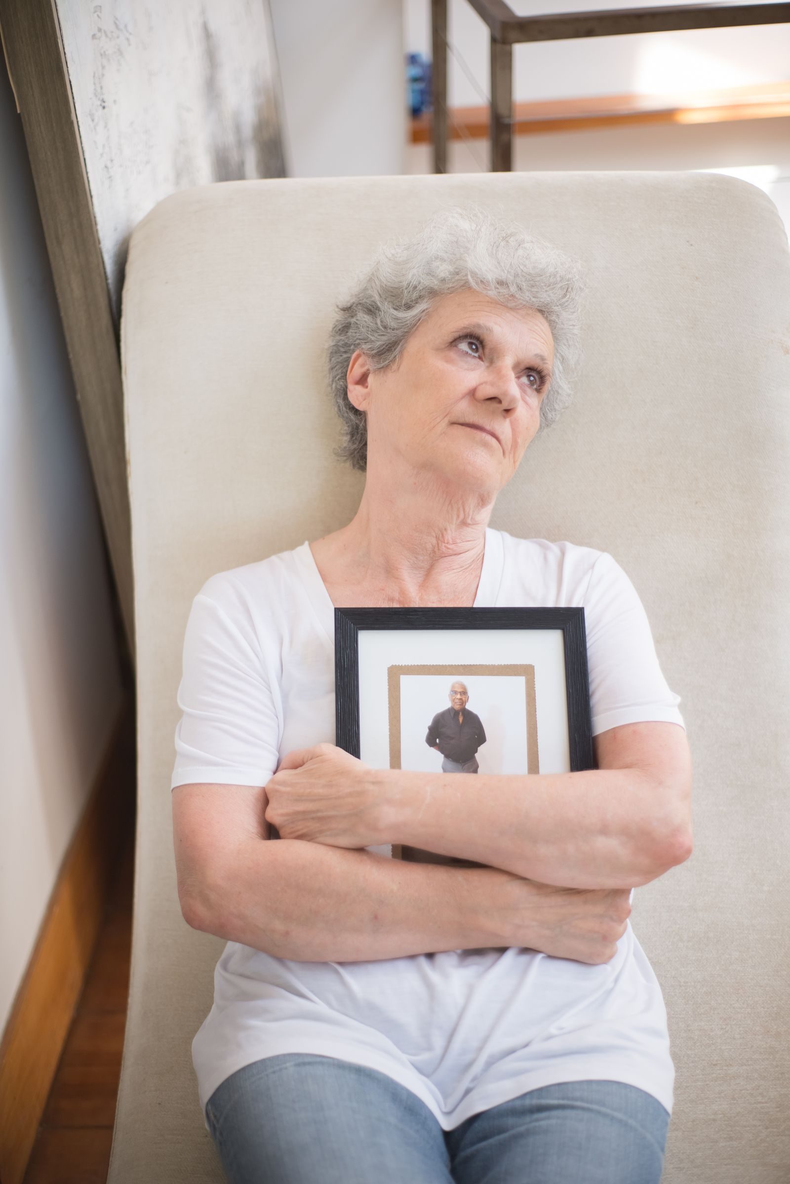 Elderly woman holding a framed photo, reflecting on memories and emotions.