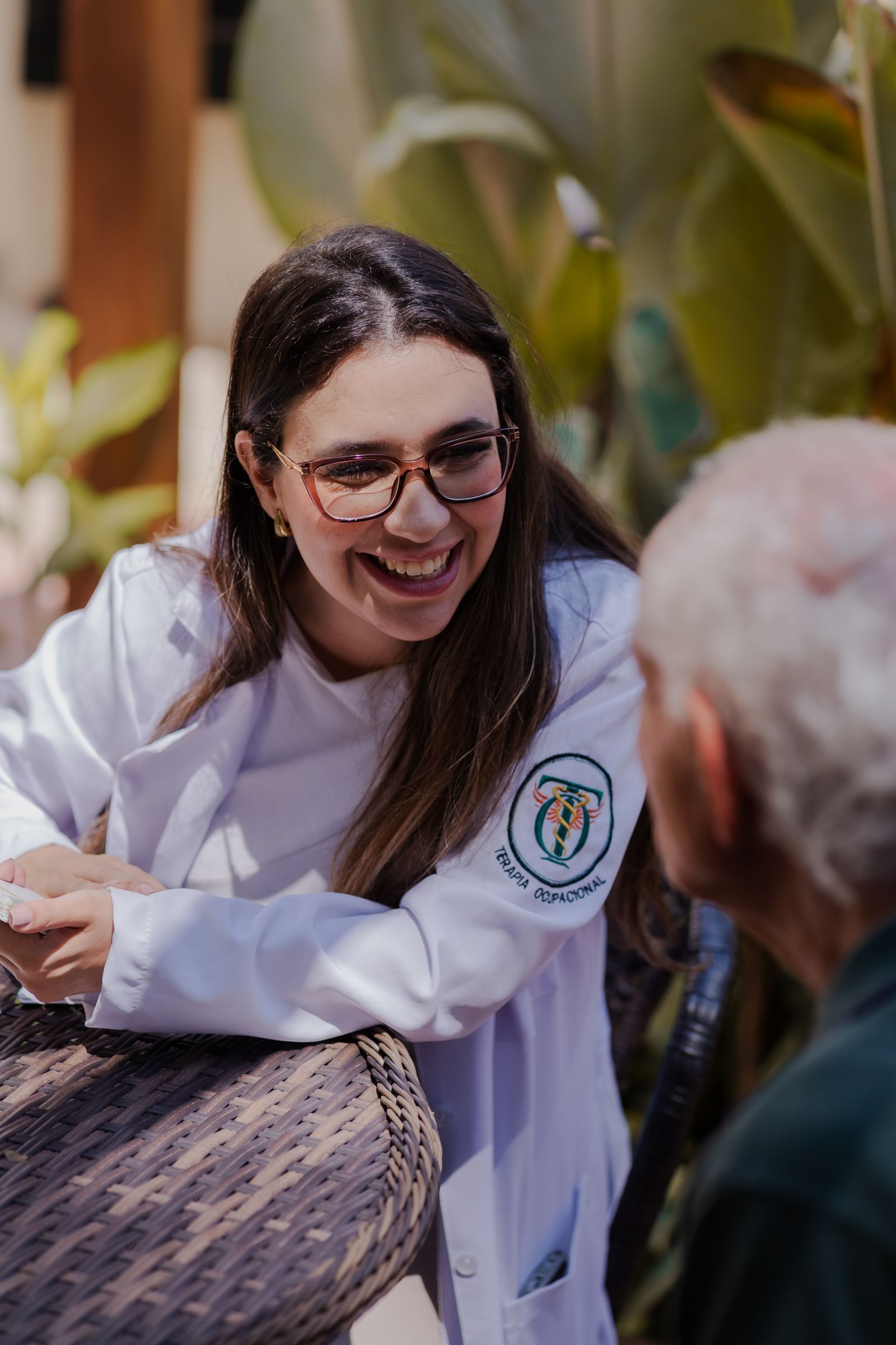 A friendly doctor in a white coat shares a warm moment outside with an older gentleman.