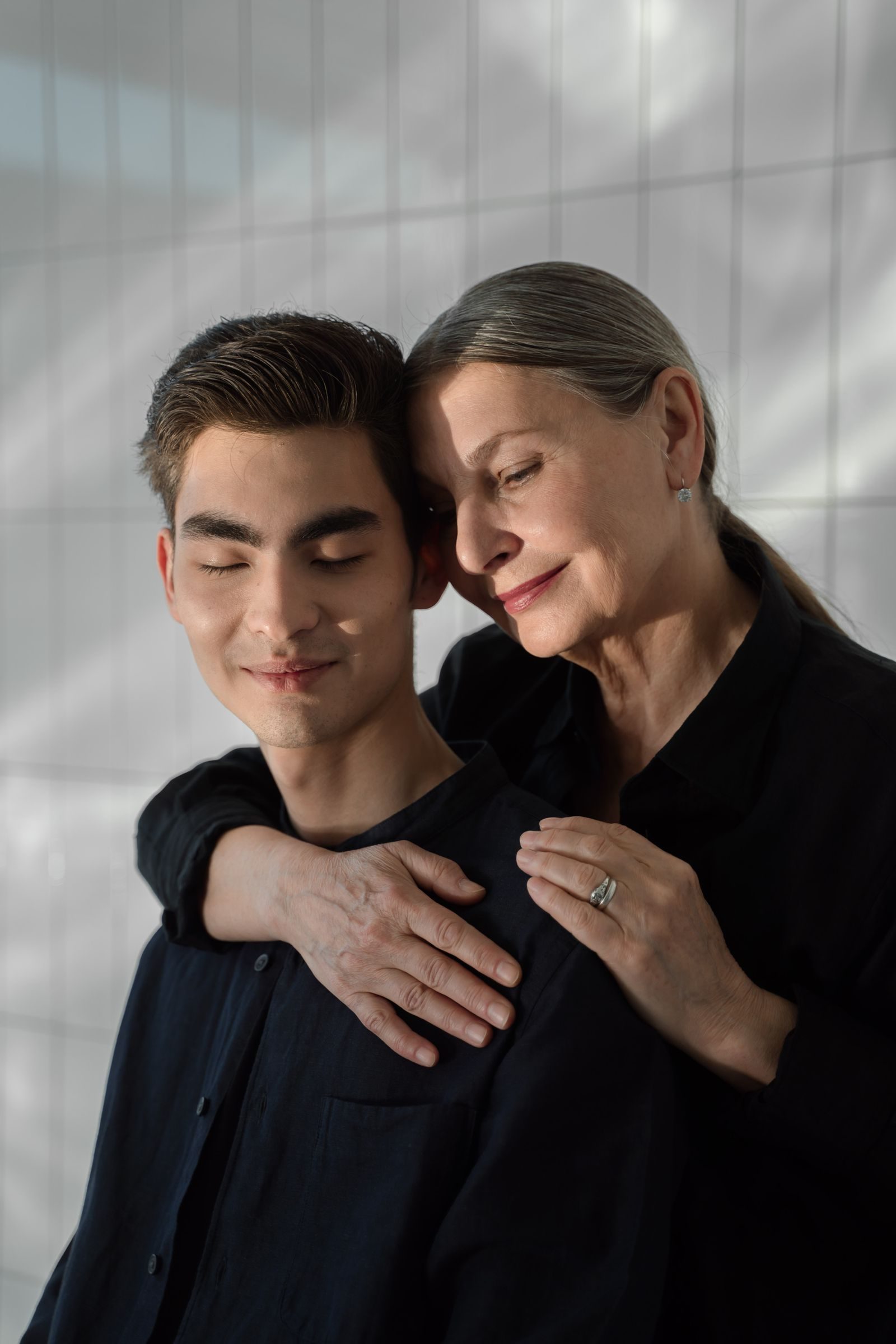 An elderly woman lovingly embraces her adult son, creating a touching family moment.