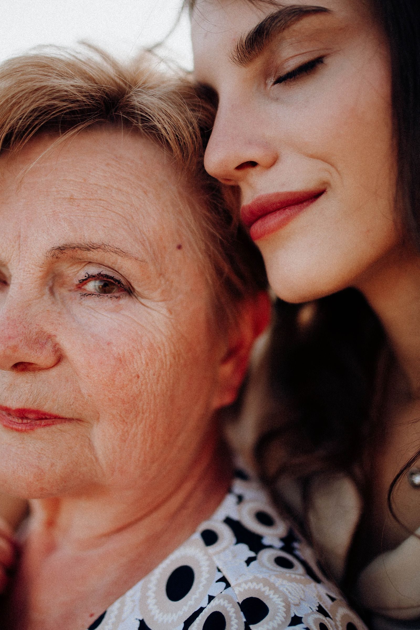 Close-up portrait of a mother and daughter sharing a quiet, intimate moment.