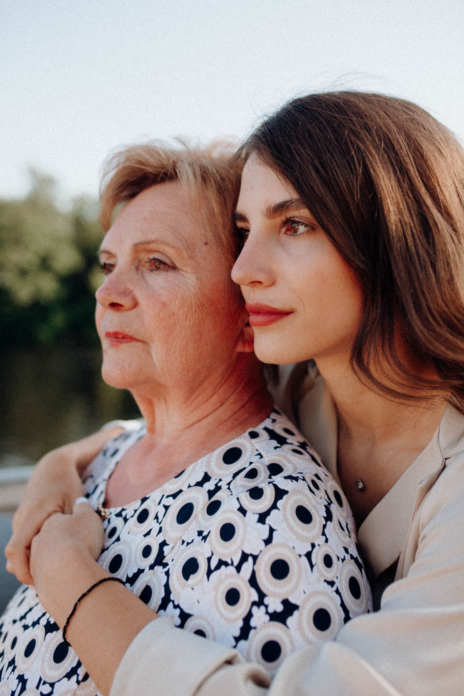 A loving moment shared between a mother and daughter in a serene outdoor setting.