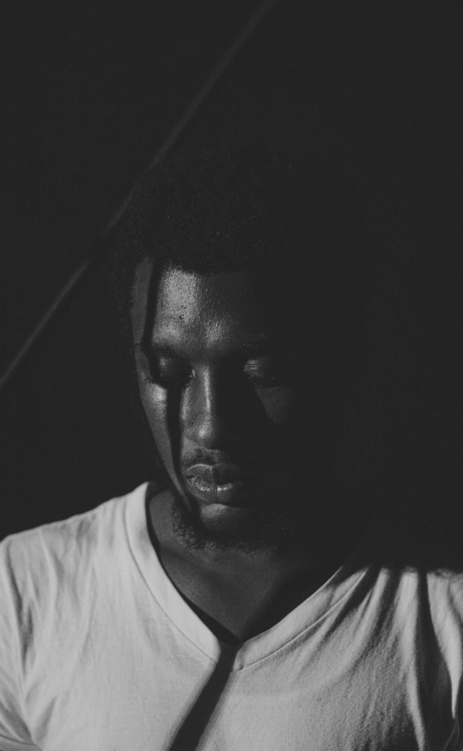 A black and white portrait of a man in deep thought, conveying emotion and solitude.