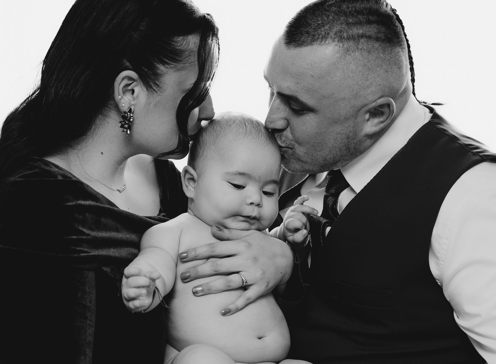 Beautiful monochrome family portrait with parents showing affection to their baby.