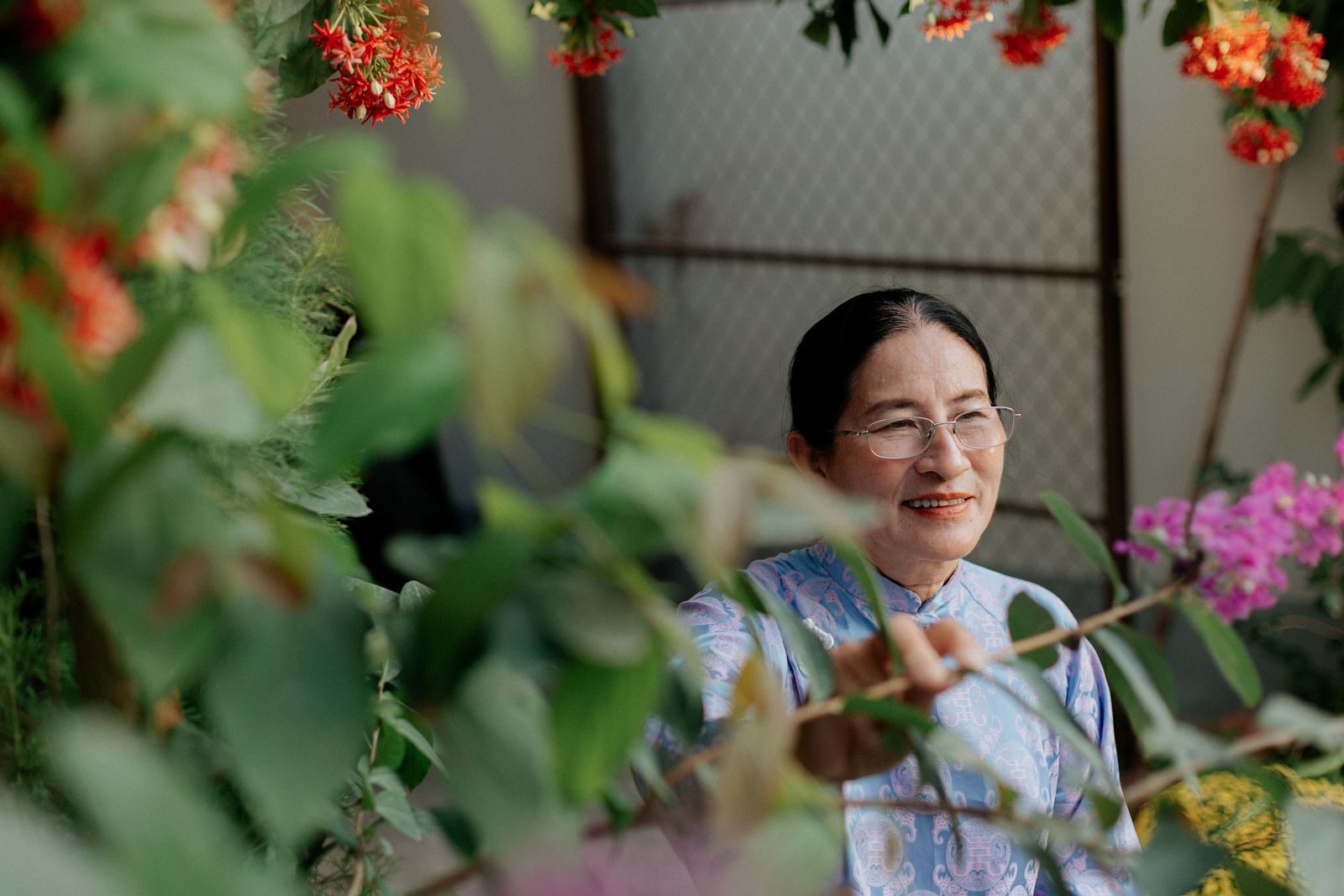 A senior woman enjoys colorful flowers in a vibrant garden setting.