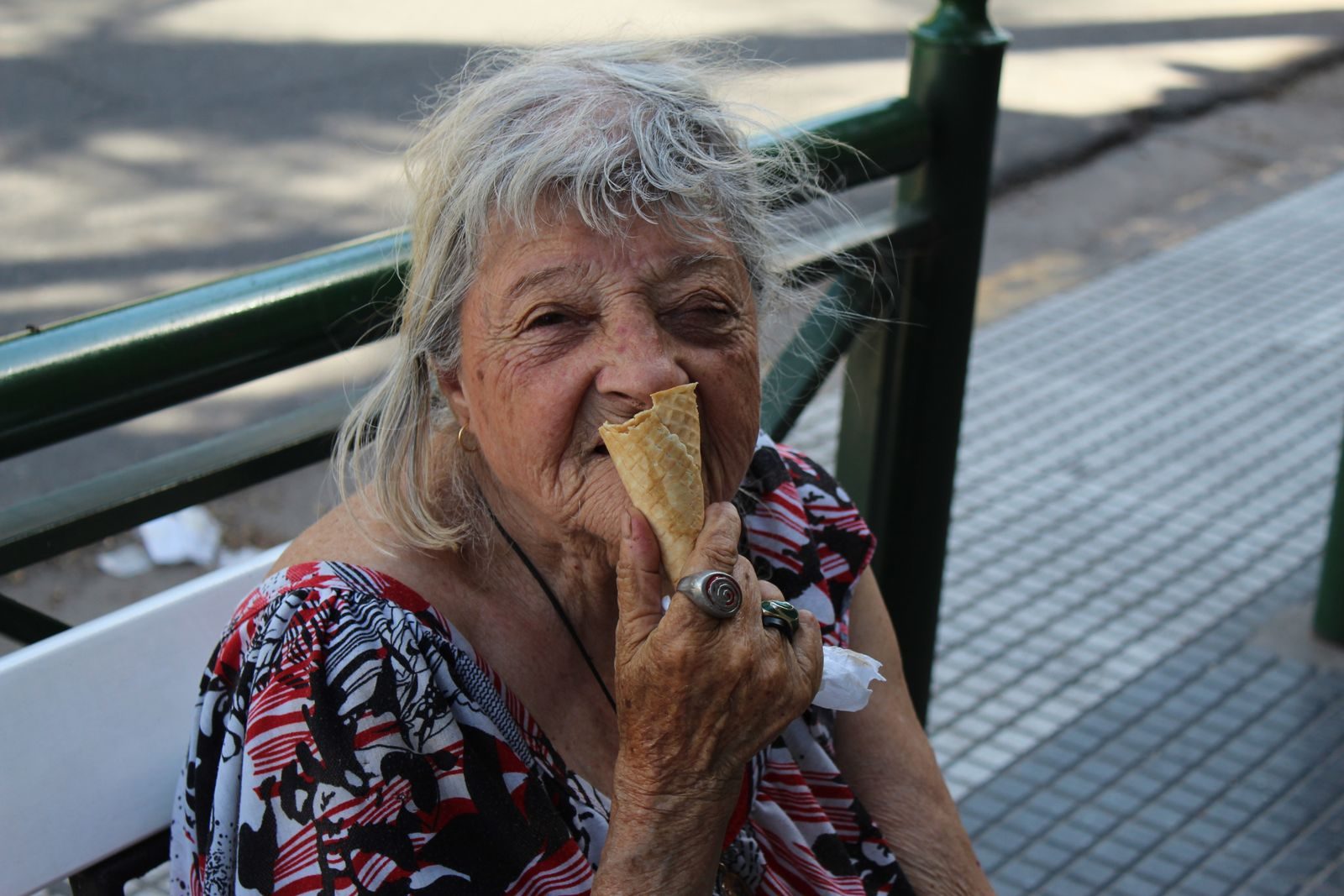 Elderly woman savoring ice cream cone on a sunny day outside. Captured candid moment.