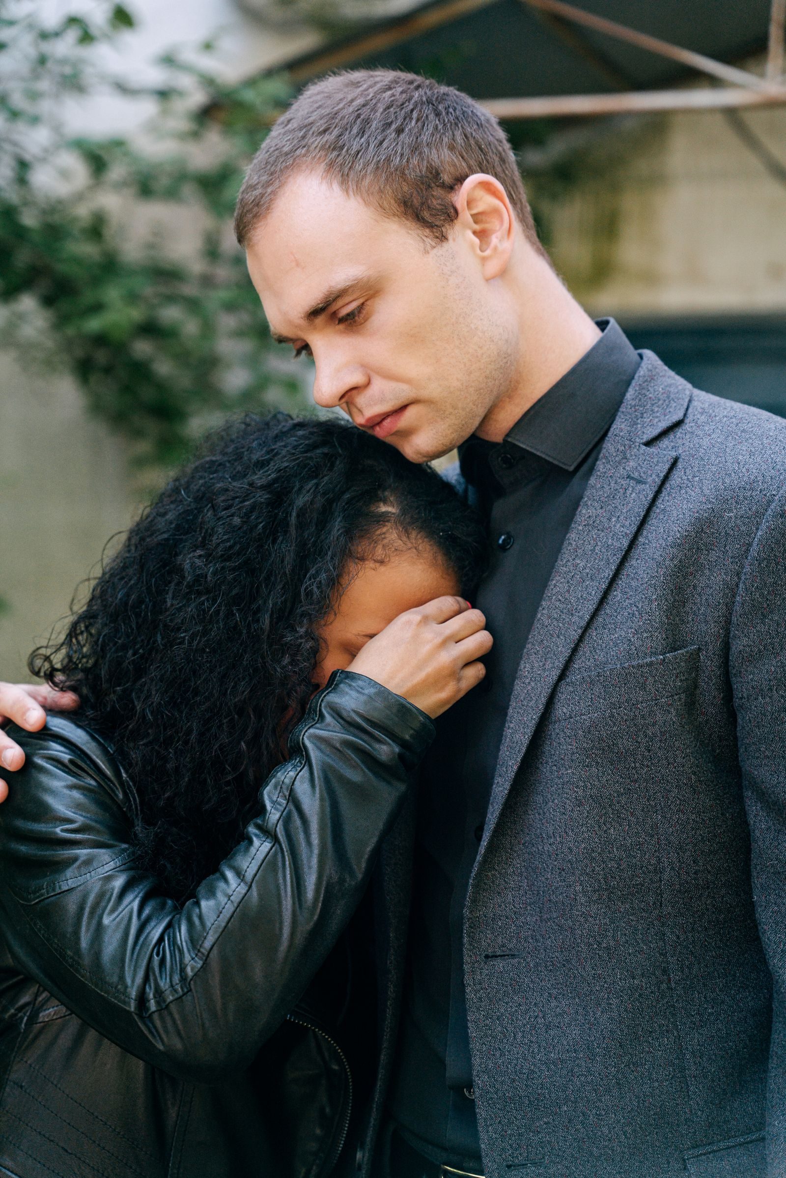 A couple embracing in comfort during a moment of grief, outdoors with a somber tone.