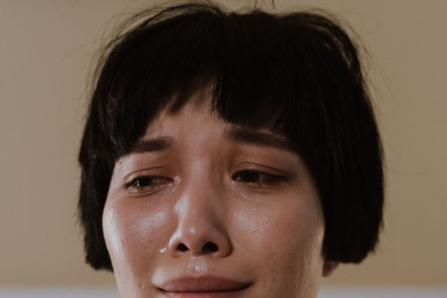 Close-up portrait of a crying woman indoors, showcasing emotions and vulnerability.