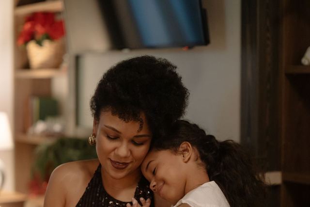 A mother and daughter share a loving hug at home during a festive holiday gathering.