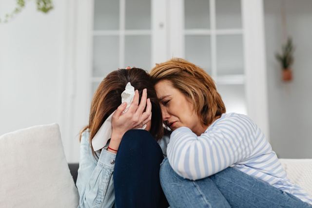 Two women share an emotional moment, conveying comfort and empathy indoors.