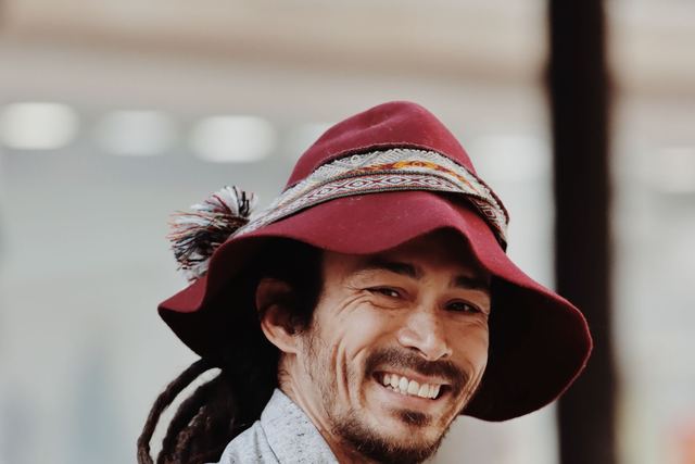 Portrait of a smiling man in a colorful hat, captured in Lisbon's lively streets.