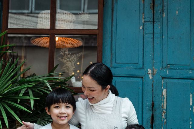 A joyful moment of a mother embracing her two children outside a rustic blue door.
