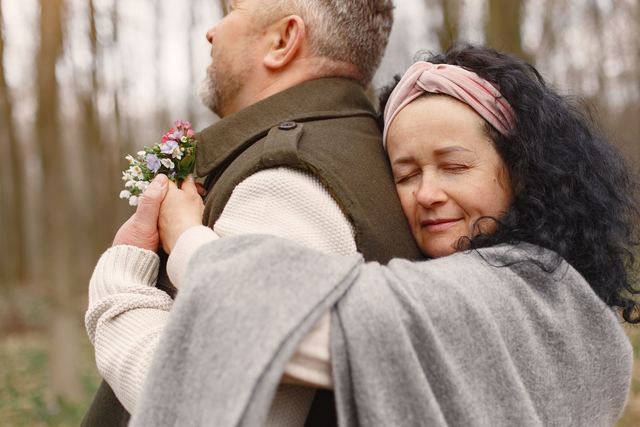 A couple sharing a tender moment with a back hug in an autumn forest.