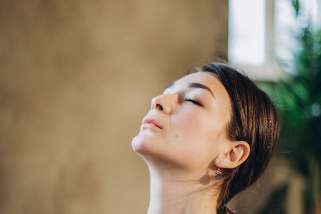 Tranquil indoor portrait of a woman in a calm and peaceful state with eyes closed.
