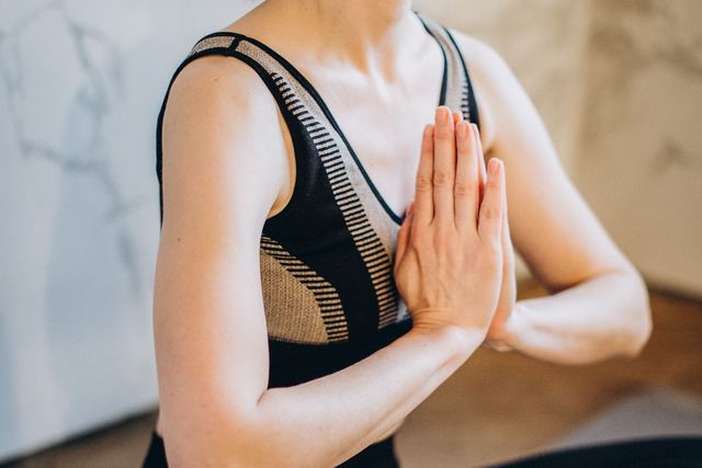 A woman in yoga attire meditating indoors in a serene pose, promoting wellness.