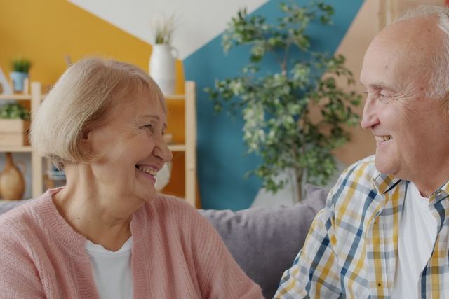 Happy senior couple sharing a joyful moment indoors with a colorful backdrop.