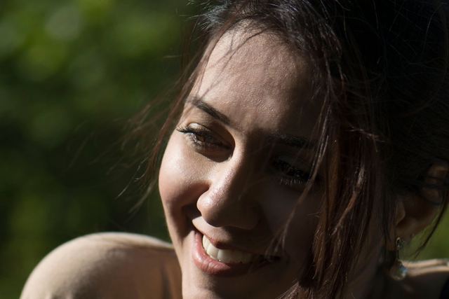 A joyful woman enjoying the sunlight outdoors, captured in natural lighting.