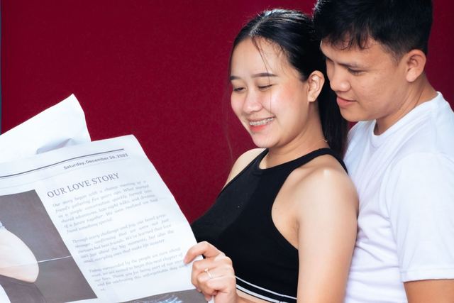 Happy couple joyfully reads pregnancy announcement together indoors.