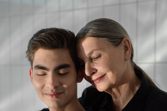 An elderly woman lovingly embraces her adult son, creating a touching family moment.