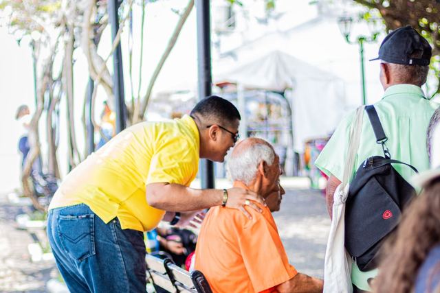Elders and a caretaker share a light moment on a sunny park day.