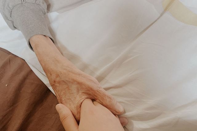 A touching moment of an adult holding a senior's hand, symbolizing love and support.
