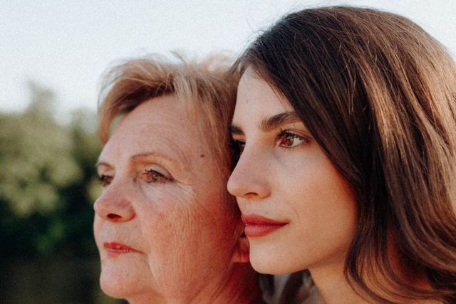A loving moment shared between a mother and daughter in a serene outdoor setting.