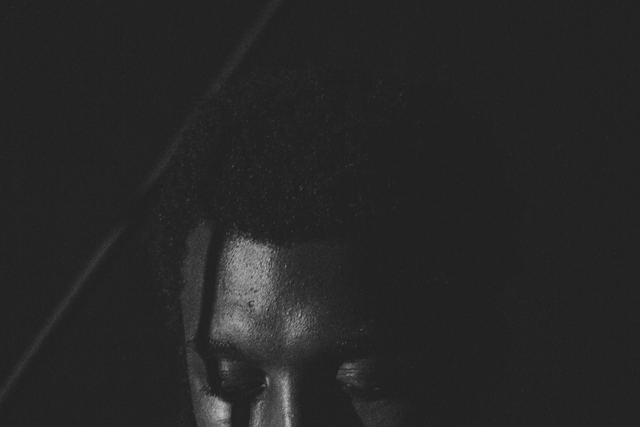 A black and white portrait of a man in deep thought, conveying emotion and solitude.