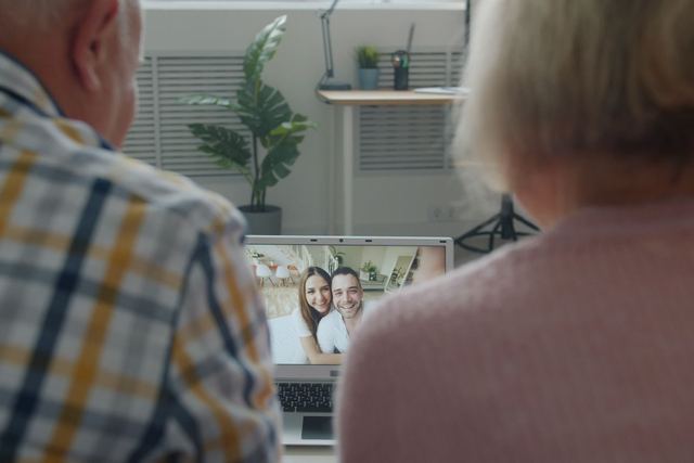 Senior couple having a video chat with family on a laptop indoors.