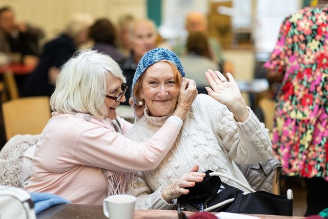 Two senior women sharing a happy moment and laughing in a cozy cafe setting.