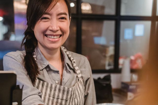 Smiling barista serving coffee at a modern cafe counter.