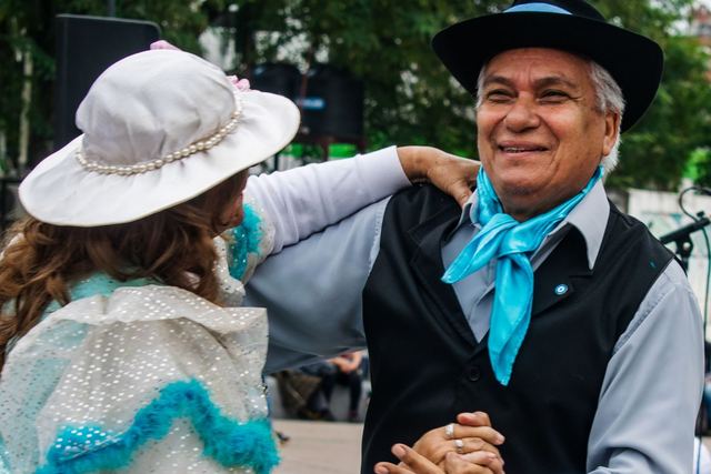Elderly couple joyfully dancing traditional Argentine dance outdoors.