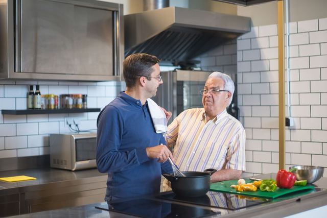 Father and son bonding in a modern kitchen while preparing a meal together.