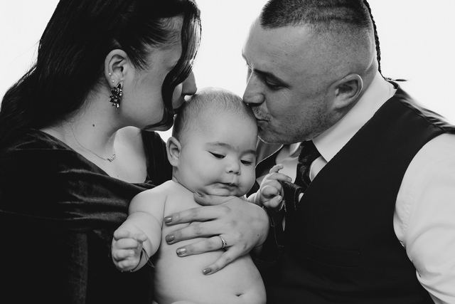 Beautiful monochrome family portrait with parents showing affection to their baby.