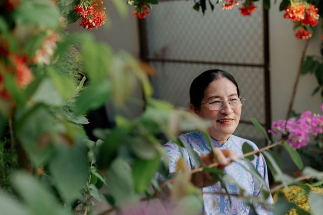 A senior woman enjoys colorful flowers in a vibrant garden setting.