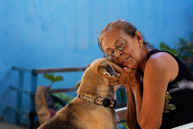 A heartwarming scene of an elderly woman lovingly embracing her pet dog outdoors.