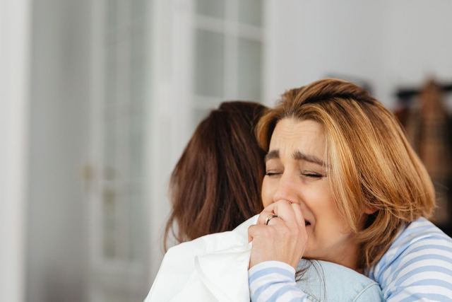 A comforting embrace between two women indoors, highlighting empathy and support.