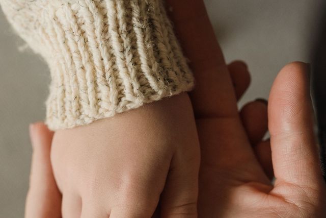 Intimate close-up of a child and adult holding hands, showing warmth and care.