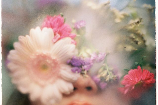 Romantic portrait with colorful flowers obscuring a woman's face, creating an ethereal effect.